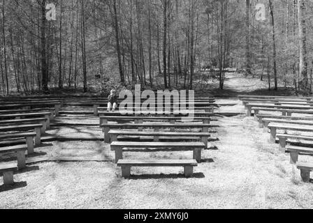 Una donna caucasica, di età compresa tra i 50 e i 55 anni, si rilassa in un anfiteatro lungo un sentiero panoramico al Davidson River Campground vicino a Brevard e Hendersonville, North Carolina. Foto Stock