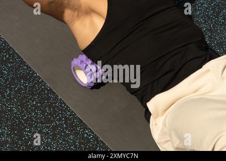 L'atleta si allunga usando per il rullo posteriore in schiuma. Primo piano. Foto Stock