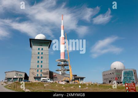 Schierke, Germania. 30 luglio 2024. Una gru del peso di diverse tonnellate si trova accanto alla torre Brocken. Sul tetto del Brockenherberge sono attualmente in fase di installazione nuove listelli per tetto. Poiché i lavori si svolgono ad altezze elevate nell'area del radar di volo, il sistema radar di volo sul Brocken è stato spento per diverse settimane. Crediti: Matthias Bein/dpa/Alamy Live News Foto Stock