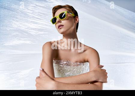 Una donna con i capelli corti che indossa gli occhiali da sole si siede avvolto in un abito a bolle d'aria. Foto Stock