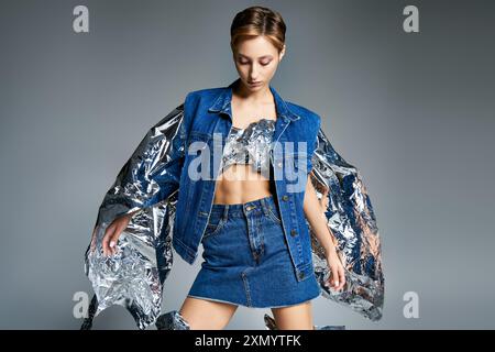 Una donna modella una giacca e una gonna in denim con dettagli metallizzati per un look alla moda sostenibile. Foto Stock