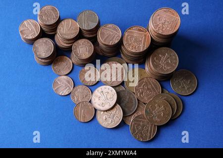 Monete da penny britanniche di basso valore su sfondo blu con monete da 1p, 2p incluse. Per molti anni ci sono state speculazioni su quando possono essere discute Foto Stock