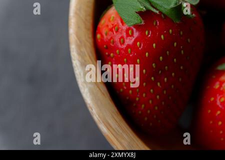Fragole fresche in cestello di legno su superficie scura. Foto Stock