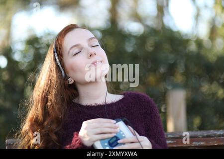 Una giovane donna ascolta la musica in modo rilassato sul suo vecchio lettore di cassette Foto Stock