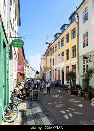 Copenaghen Danimarca 21 luglio 2024, Una strada vivace di Copenaghen è piena di attività mentre i visitatori esplorano edifici colorati, caffè e negozi locali Foto Stock