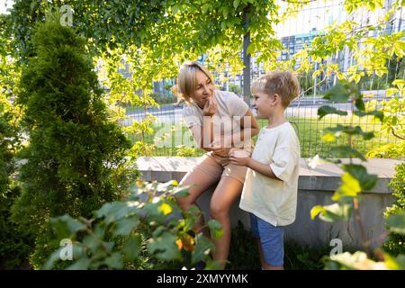 Mamma ama trascorrere momenti di qualità con i suoi due figli al parco giochi in un pomeriggio di sole Foto Stock