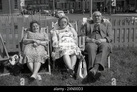 Anni '1960, un anziano gentiluomo e due signore sedute su sdraio nel giardino anteriore della loro pensione per le vacanze, in prossimità di Red Bank Rd, Blackpool, Inghilterra, Regno Unito. Foto Stock