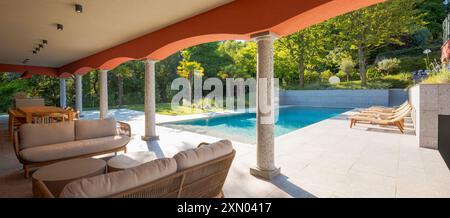 Vista di una splendida piscina di un albergo privato in piena luce del giorno. Un salotto sotto gli archi per rilassarsi. Ambiente lussuoso Foto Stock