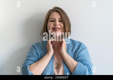 Donna sorridente e taglia che tocca il collo, esprimendo sicurezza e positività. Foto Stock