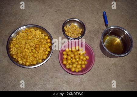 Uva spina, caramelle Amla, pezzetti di amla e semi tenuti in piatti e piatti, uva spina bollita gialla Foto Stock