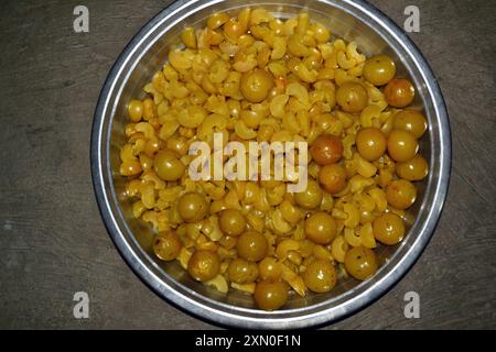 Uva spina, caramelle Amla, pezzetti di amla e semi tenuti in piatti e piatti, uva spina bollita gialla Foto Stock