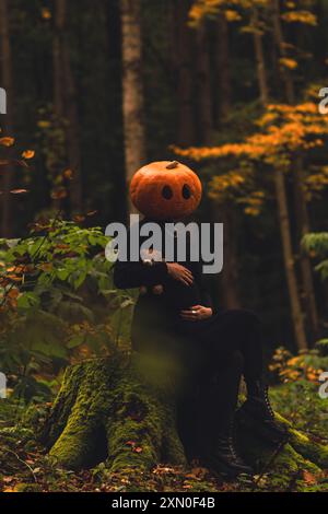 donna spaventosa con testa di zucca nella foresta con giocattolo Foto Stock