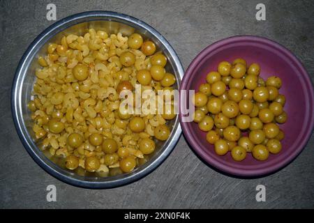 Uva spina, caramelle Amla, pezzetti di amla e semi tenuti in piatti e piatti, uva spina bollita gialla Foto Stock