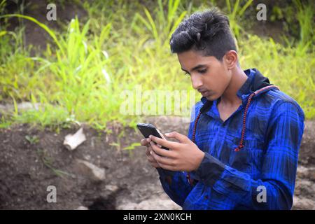 Ragazzo modello indiano in abito blu in posa, sfondo verde all'aperto. Foto Stock