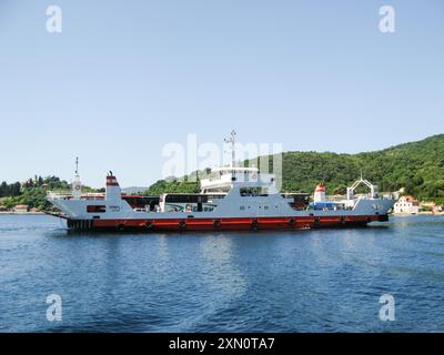 Cattaro, Montenegro, giugno 2011: Vista di un traghetto che attraversa la baia di Cattaro, carico di automobili, autobus e persone. Sfondo della città costiera e delle verdi colline. Foto Stock