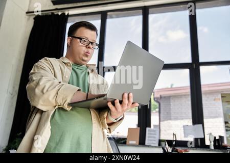 Un giovane con la sindrome di Down usa un laptop in ufficio. Foto Stock