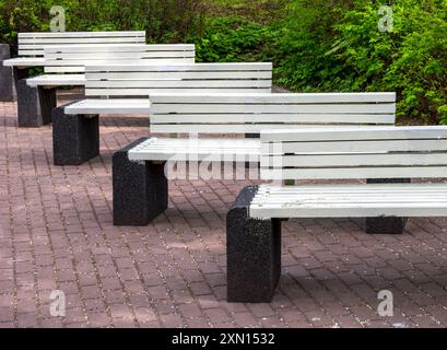 Fila di panche di legno su blocchi di cemento in un parco Foto Stock