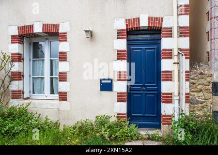 Porta d'ingresso blu di una tipica casa bianca sul mare con un contorno di mattoni rossi e bianchi e una cassetta delle lettere blu. Foto Stock