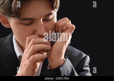 Artista maschile che suona armonica su sfondo scuro, primo piano Foto Stock