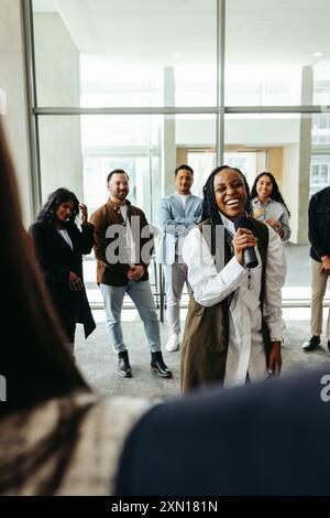 Leader di successo che ispira la forza lavoro durante una riunione aziendale motivazionale, promuovendo il lavoro di squadra e la leadership tra colleghi diversi. Foto Stock