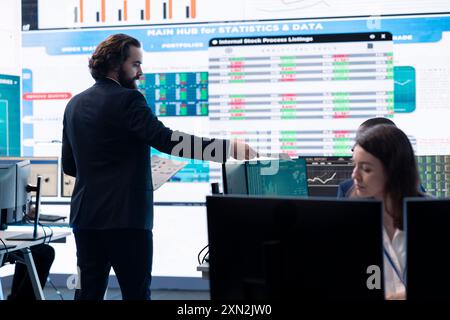 Responsabile finanziario che informa i membri del suo team sui nuovi obiettivi aziendali, presentando il loro schema di budget con le spese. Allocazione delle risorse e pianificazione dei progetti nella sala di controllo. Foto Stock