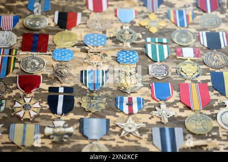 KIEV, UCRAINA - 10 LUGLIO 2024 molte medaglie militari statunitensi su sfondo mimetico. Medaglie degli Stati Uniti. Primo piano di oggetti di scena fatti a mano in carta Foto Stock