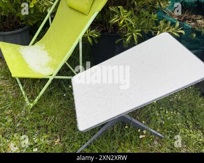 Francoforte, Germania - 18 marzo 2024: Grandine che coprono una poltrona per bambini e un'antenna Internet Starlink SpaceX in un giardino, evidenziando l'impatto del maltempo e collegandosi ai concetti del cambiamento climatico Foto Stock