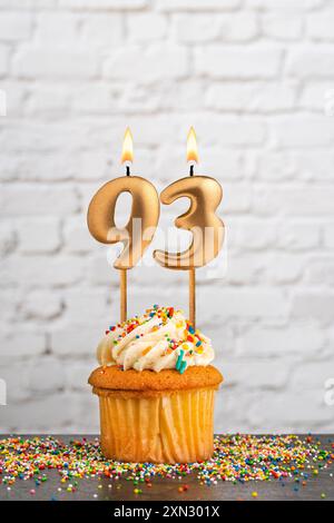 Candela di compleanno dorata numero 93 con cupcake - sfondo bianco della parete Foto Stock