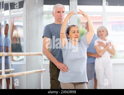Coppia di ballerini maturi contemporanei che eseguono graziose coreografie, allenando il balletto entrechat in posa nella sala del balletto Foto Stock