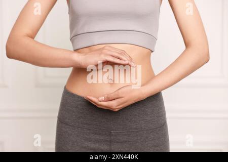 Digestione sana. Donna che tiene qualcosa vicino alla pancia dentro, primo piano Foto Stock