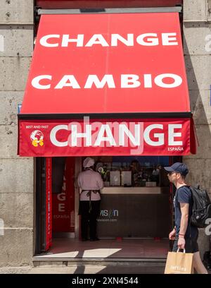 Madrid, Spagna, 06.19.2024: Negozio di cambio valuta, Madrid, con tenda rossa davanti con le parole cambio e cambio su di esso, cliente donna con chef unif Foto Stock