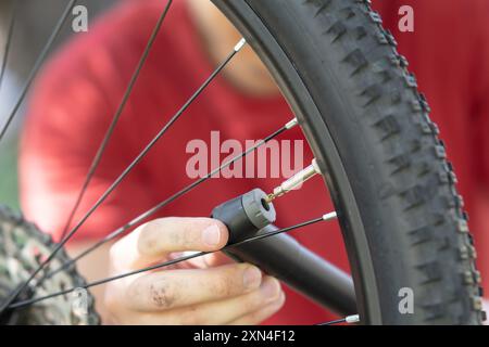 Uomo che pompa una ruota da bici con una piccola pompa a mano, giovane che gonfia una ruota da bicicletta con una piccola pompa da vicino Foto Stock