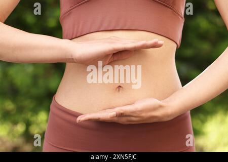 Digestione sana. Donna che tiene qualcosa vicino alla pancia all'aperto, primo piano Foto Stock