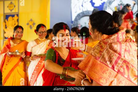 Birbhum, Bengala Occidentale, India - 24 ottobre 2023: Una bella donna in abito tradizionale con faccia sorridente di colore rosso che gioca con sindoor durante l'ultimo Foto Stock