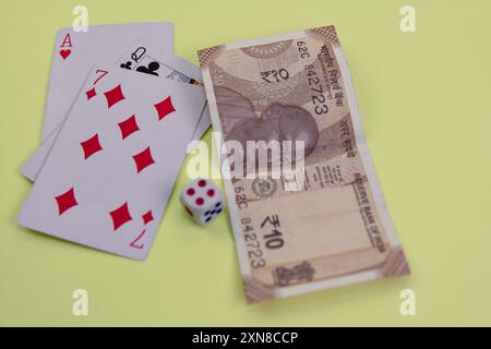 Una banconota da dieci rupie, carte da gioco e dadi creano la scena per un gioco d'azzardo. Alto rischio, alta ricompensa? proibito Foto Stock