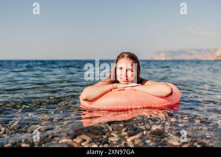 Una donna sta posando su una zattera gonfiabile rossa nell'oceano Foto Stock