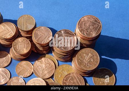 Monete inglesi basse su sfondo blu con forte illuminazione direzionale, monete da 1p, 2p incluse . Per molti anni ci sono state speculazioni in merito Foto Stock