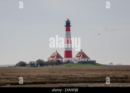 Segnale di spedizione da più di 100 anni. Il faro di Westerheversand visto da ovest. Costruito nel 1906 nelle saline del Mare di Wadden vicino a Husum, è un punto di riferimento storico della costa tedesca del Mare del Nord e una popolare attrazione turistica. Si trova su di un basso edificio ad appena un paio di centinaia di metri dall'attuale linea d'acqua. Foto Stock