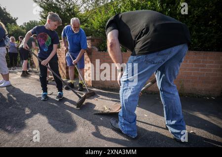 ***PERMESSO GENITORIALE CONCESSO*** i volontari spazzano Sussex Road a Southport, Merseyside, dopo che gli agenti di polizia hanno subito gravi lesioni quando mattoni, pietre e bottiglie sono stati gettati e le auto sono state accese durante le violente proteste a seguito di una veglia per tre ragazze uccise in un attacco di coltello in un club vacanze a tema Taylor Swift lunedì. Data foto: Mercoledì 31 luglio 2024. Foto Stock