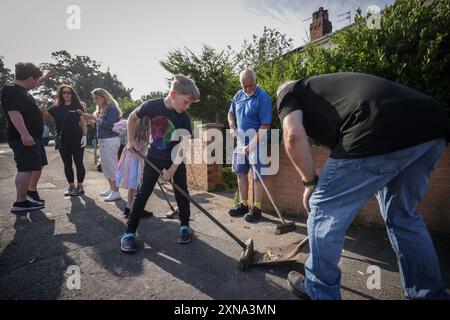 ***PERMESSO GENITORIALE CONCESSO*** i volontari spazzano Sussex Road a Southport, Merseyside, dopo che gli agenti di polizia hanno subito gravi lesioni quando mattoni, pietre e bottiglie sono stati gettati e le auto sono state accese durante le violente proteste a seguito di una veglia per tre ragazze uccise in un attacco di coltello in un club vacanze a tema Taylor Swift lunedì. Data foto: Mercoledì 31 luglio 2024. Foto Stock