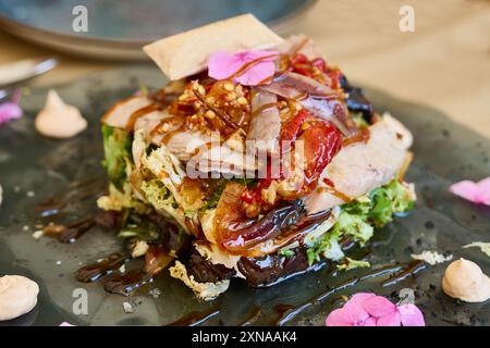 Insalata di pancia di tonno con peperoni rossi, noci e varie lattughe su un piatto di vetro, condita con aceto di Modena Foto Stock