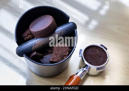 Caffè compattato macinato in scatola con portafiltro accanto. I fondi di caffè sono eccellenti fertilizzanti naturali e organici. Foto Stock