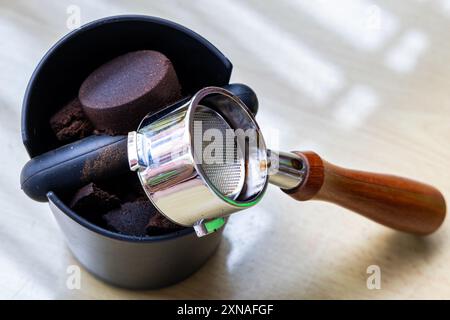 Caffè compattato macinato in scatola con portafiltro accanto. I fondi di caffè sono eccellenti fertilizzanti naturali e organici. Foto Stock