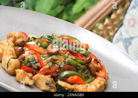 Un piatto di pollo fritto in padella con un assortimento di verdure colorate, tra cui peperoni, funghi ed erbe verdi brillanti, guarnite con roa Foto Stock
