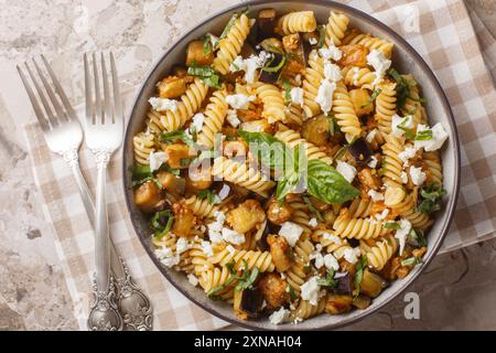 Piatto di pasta tradizionale con aglio saltato di melanzane e condito con primo piano di feta sulla ciotola sul tavolo. Vista dall'alto orizzontale Foto Stock