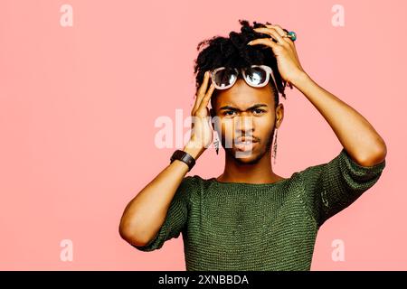 Ritratto di un giovane uomo che tiene la testa, isolato su sfondo rosa dello studio Foto Stock