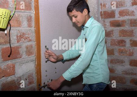 Adolescente indiano che sbatte la porta, indossa una camicia verde chiaro con punti neri Foto Stock