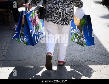 Berlino, Germania. 31 luglio 2024. Una donna esce dai grandi magazzini di lusso Galeries Lafayette in Friedrichstrasse a Berlino-Mitte con diverse borse per la spesa. La catena francese di grandi magazzini Galeries Lafayette sta chiudendo oggi la filiale di Berlino nel quartiere 207. Il Senato di Berlino sta valutando la possibilità di trasferire la Biblioteca centrale e regionale di Berlino (ZLB) nel complesso dell'edificio. Crediti: Bernd von Jutrczenka/dpa/Alamy Live News Foto Stock