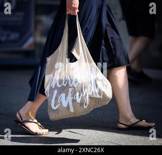 Berlino, Germania. 31 luglio 2024. Una donna esce dai grandi magazzini di lusso Galeries Lafayette in Friedrichstrasse a Berlino-Mitte con una borsa per la spesa. La catena francese di grandi magazzini Galeries Lafayette sta chiudendo oggi la filiale di Berlino nel quartiere 207. Il Senato di Berlino sta valutando la possibilità di trasferire la Biblioteca centrale e regionale di Berlino (ZLB) nel complesso dell'edificio. Crediti: Bernd von Jutrczenka/dpa/Alamy Live News Foto Stock