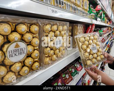 Petaling Jaya, Selangor, Malesia - 29 luglio 2024 : Una foto ravvicinata di una mano di una donna che prende una scatola di cioccolato Ferrero Rocher da un des Foto Stock